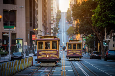Classic view of historic traditional Cable Cars riding on famous California Street in beautiful morning light at sunrise in summer, San Francisco, USA
